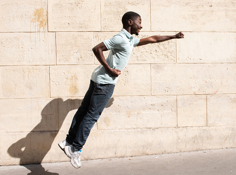 Profile portrait happy young man jumping with arm outstretch with punch
