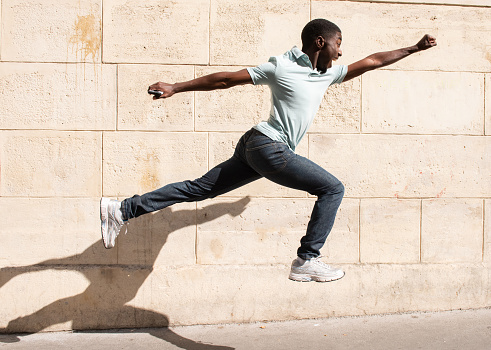 Profile portrait happy African American man jumping with arms outstretched