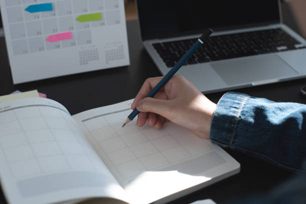 istock Event planner timetable agenda plan on year 2023 schedule event. Business woman checking timetable, taking note on calendar planner notebook on office table. Calendar event plan, work planning, mockup 1643288107