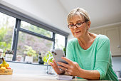 Senior woman at home using a mobile app on her cell phone