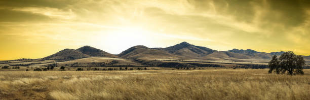 istock Panorama of a distant mountain range with hills covered in grass in the forground with a dramatic sunset 1643335474
