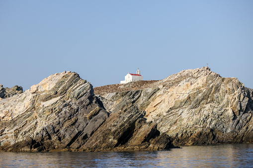 Mykonos, Greece - July 21, 2023: A clifftop cross and church on an island off the shores of Mykonos Town in Greece