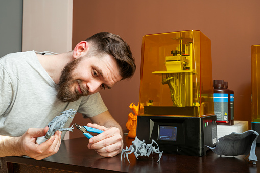 Man cutting excess plastic from 3d printer object