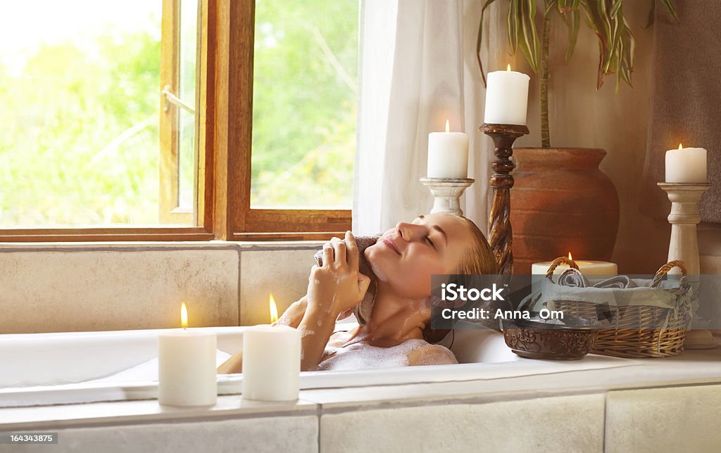 Cute female taking bath Image of nice female taking bath in gorgeous bathroom with aroma candles, alternative treatment, luxury lifestyle, spa resort, beauty care, hygiene and pampering, wellness and wellbeing concept Adult Stock Photo