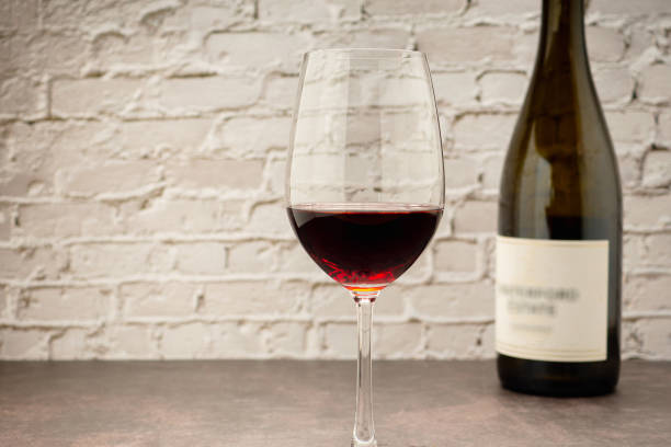 istock Red wine glass and bottle with white brick wall background 1643448742