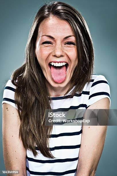 Joyous Young Woman In Striped Top Sticking Out Her Tongue Stock Photo - Download Image Now