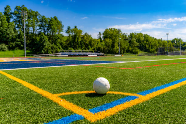 多目的人工芝フィールドの隅にある白いアメリカンサッカーボールの午後の写真。 - high school sports ストックフォトと画像