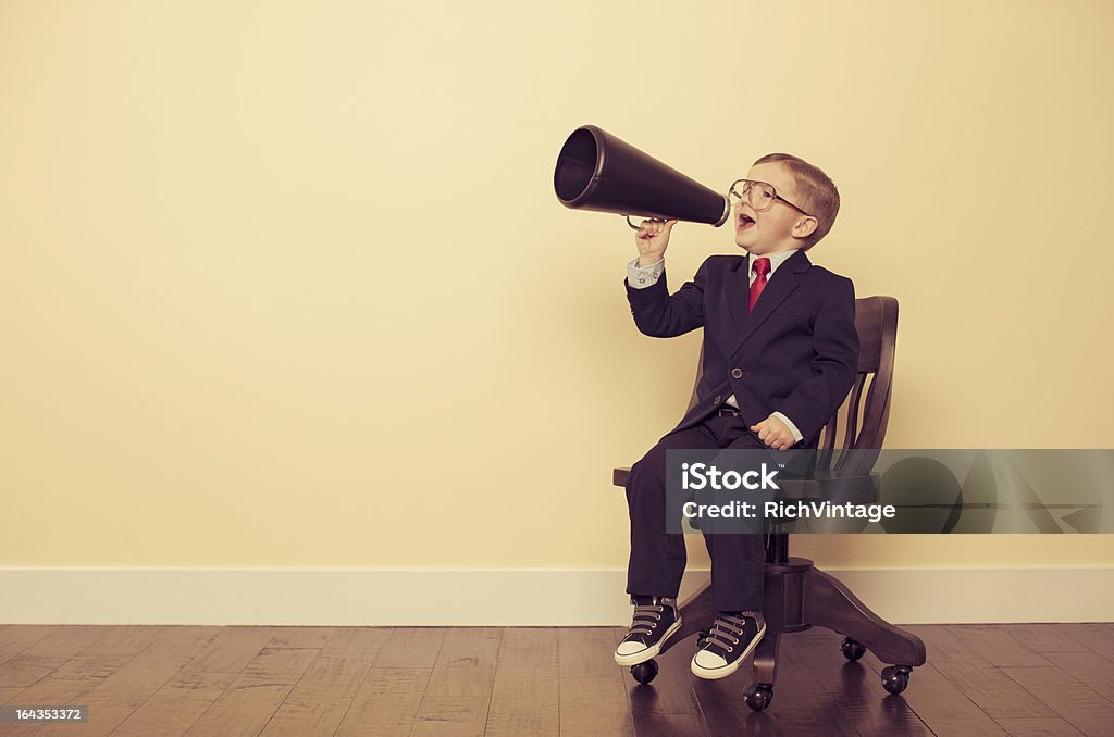 Jeune garçon d'affaires assis dans une chaise Yelling au porte-voix - Photo de Porte-voix libre de droits