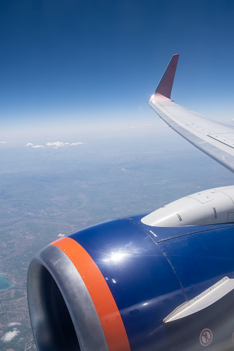 Airplane flight. Wing of an airplane flying above the clouds. View from the window of the plane. Airplane, Aircraft. Traveling by air. Aircraft's wing and land seen through the illuminator.