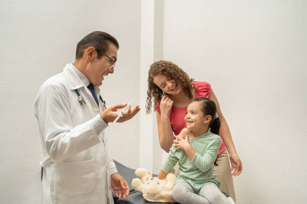 mother and doctor talking and smiling to little girl building confidence before being injected or vaccinated. Pediatrician holding a syringe about to put an injection to a child or kid mother and doctor talking and smiling to little girl building confidence before being injected or vaccinated. Pediatrician holding a syringe about to put an injection to a child or kid injecting flu virus vaccination child stock pictures, royalty-free photos & images