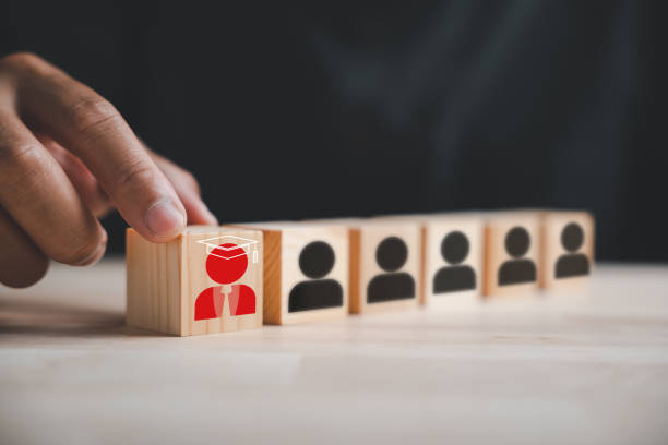 istock Hand reaching for red human icon on wooden block 1643599378