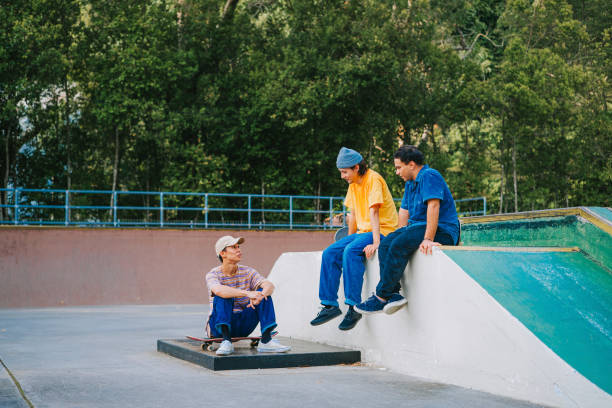 istock 3 skateboarders resting in skateboard park after practicing talking 1643600684
