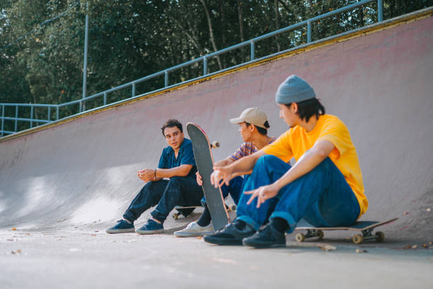 istock 3 skateboarders resting in skateboard park after practicing talking 1643600747