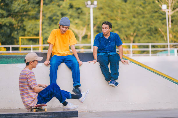 istock 3 skateboarders resting in skateboard park after practicing talking 1643600790