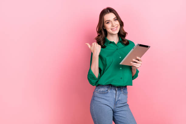 Photo of pretty shiny lady wear green shirt working modern gadget thumb empty space isolated pink color background stock photo