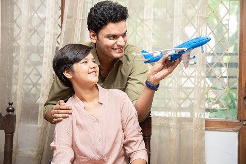 Happy indian father and daughter play with toy aeroplane, dream to become a pilot or air hostess. young girl goals to flying abroad.