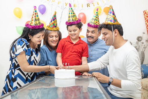 Happy Indian asian multi generational family celebrate children's birthday party.