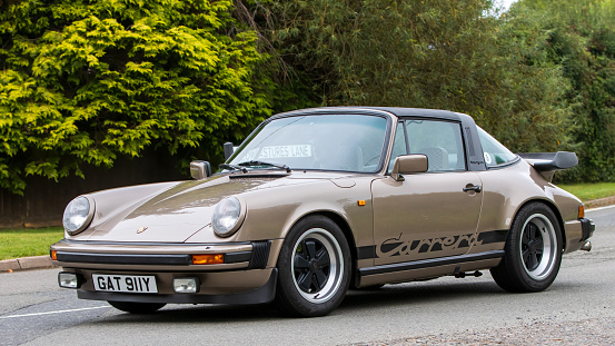 Whittlebury,Northants,UK -Aug 26th 2023: 1982 bronze Porsche Carrera car travelling on an English country road
