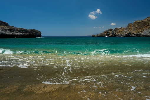 A scenic beach with clear, pristine water and rolling waves.