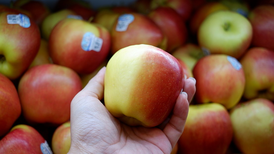 hand holding an apple with apples background.