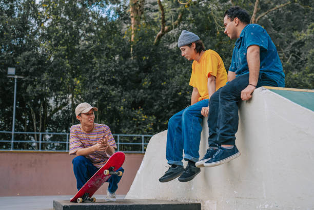 istock 3 skateboarders resting in skateboard park after practicing talking 1643747669