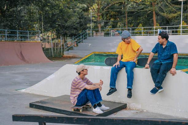 istock 3 skateboarders resting in skateboard park after practicing talking 1643747883