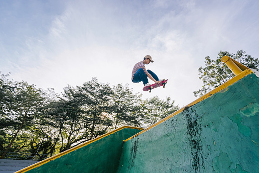 Asian Chinese skateboarder in action mid air skateboard park