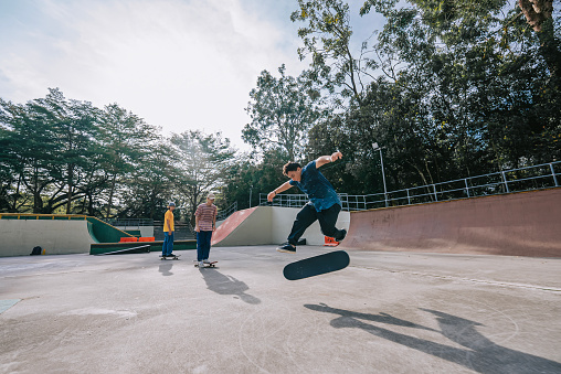 Young men enjoy skateboarding ollie in skateboard park weekend morning