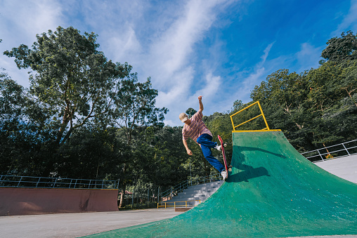 Asian Chinese Young man enjoy skateboarding in skateboard park weekend morning