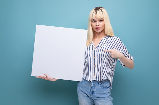blonde young female adult in blouse holding white board isolated background.