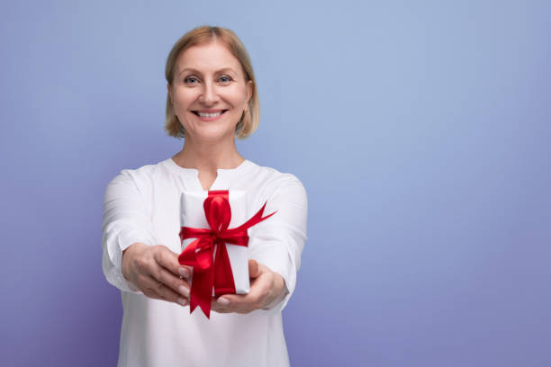 istock satisfied middle aged woman with gift box smiling 1643800465