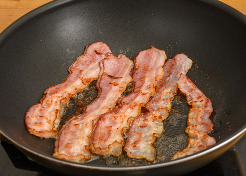 Bacon in slices, bacon fried in a pan, isolated closeup