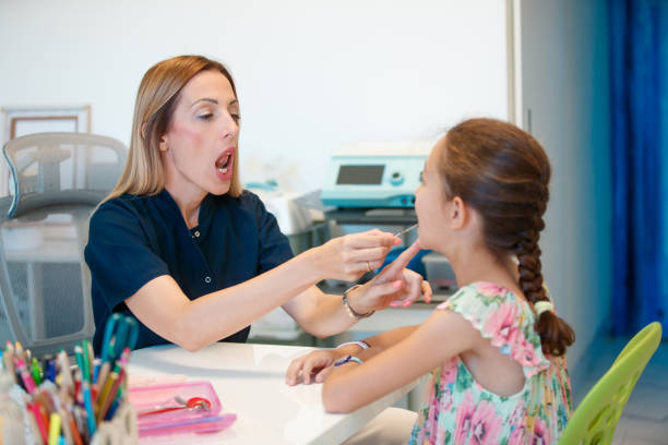 istock Female doctor using tool for speech therapy, girl at the appointment 1643814165