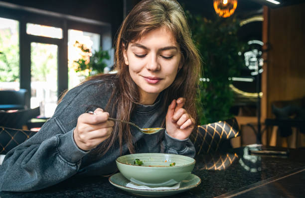 mulher atraente está comendo sopa de legumes em um café. - eating eat silverware horizontal - fotografias e filmes do acervo