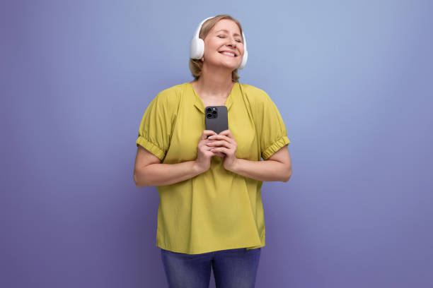 istock joyful blond mature woman watching video on smartphone using headphones 1643826985