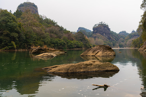 Full lenght of family in a natural aquatic environment  where mom sits on a platform by the river while children use fishing rods and dad stands back turned.