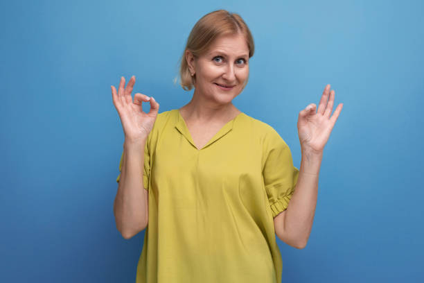 istock cute blond middle aged woman with an idea points her finger to the side in studio 1643827567