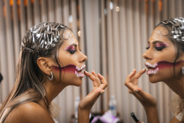 Preparations for the Halloween party, detail of a client who has finished her makeup looking in the mirror and checking her lip Preparations for the Halloween party, detail of a client who has finished her makeup looking in the mirror and checking her lip drag shw stock pictures, royalty-free photos & images