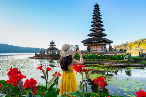 Young woman tourist relaxing and enjoying the beautiful view at Ulun Danu Beratan temple in Bali, Indonesia stock photo