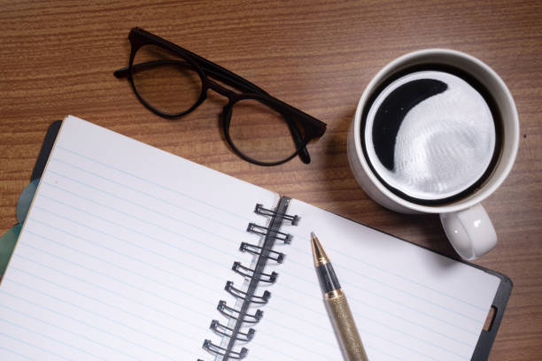 istock Top view of black coffee cup notebook and eye wear at table 1643829261