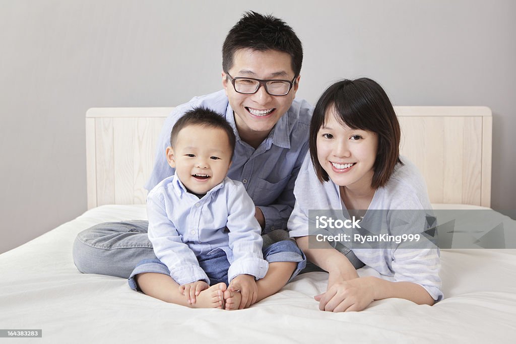 happy family sitting on white bed A happy family lying on white bed in the bedroom with gray wall for copy space, asian people Asia Stock Photo