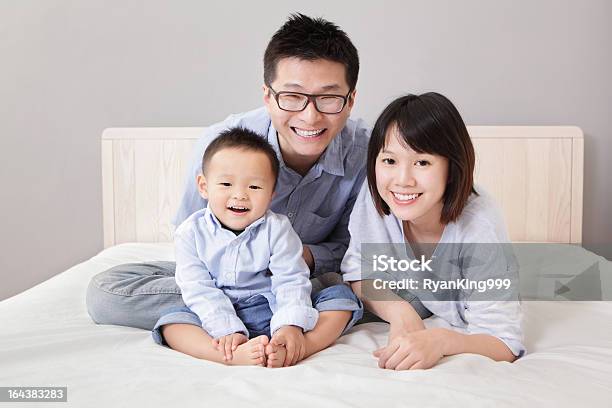Happy Family Sitting On White Bed Stock Photo - Download Image Now - Asia, Asian and Indian Ethnicities, Family