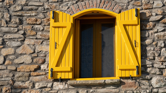 mustard yellow shutters of a Mediterranean stone house in Gokceada, Turkey, Canakkale