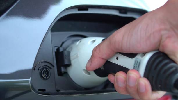 istock Open - close lid charging, Close up hand man  inserting plug into charging electric car. 1643843461