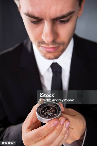 Hombre De Negocios Mirando A Una Brújula Foto de stock y más banco de imágenes de Adulto - Adulto, Agarrar, Azul