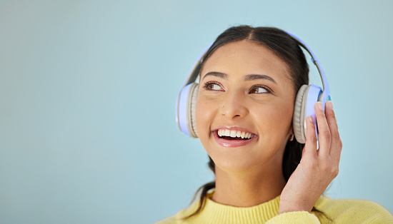 Woman with smile, headphones and mockup in studio for social media post, mobile app and streaming radio site. Podcast, music media subscription and happy girl with sound on blue background space.
