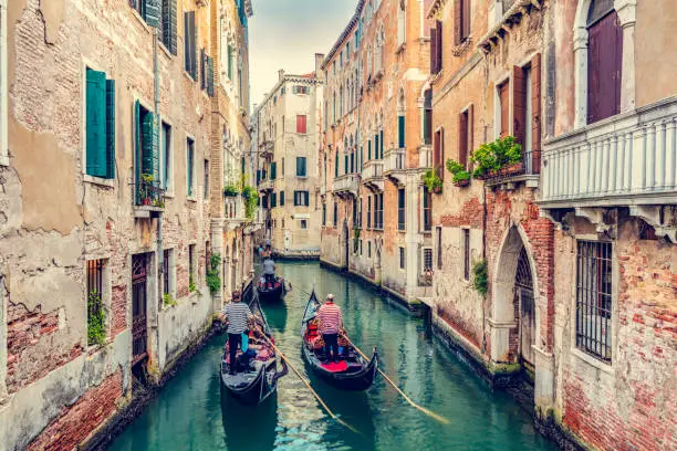 Photo of Gondolier rowing gondola on canal in Venice, Italy.