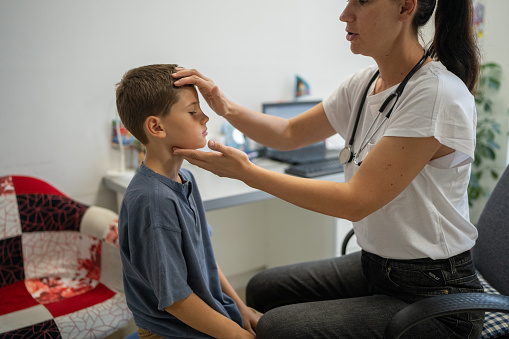 Female pediatrician examining a little boy at doctor's office