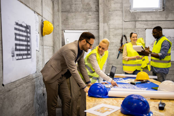 istock Team of experienced architects and engineers sharing ideas and looking at building plant at construction site. 1643916347