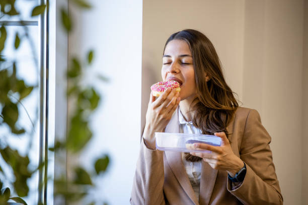 istock Beautiful woman eating donuts and drinking coffee at work. 1643928220
